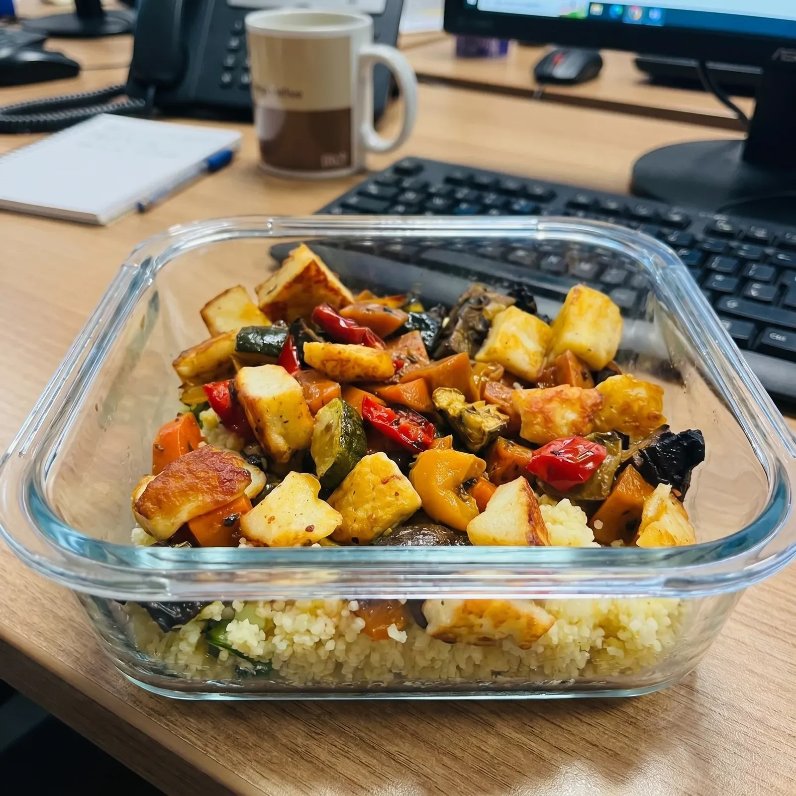 Mitgenommenes Mittagessen am Arbeitsplatz: Couscous mit Ofengemüse und Halloumi in einer Glas-Vorratsdose